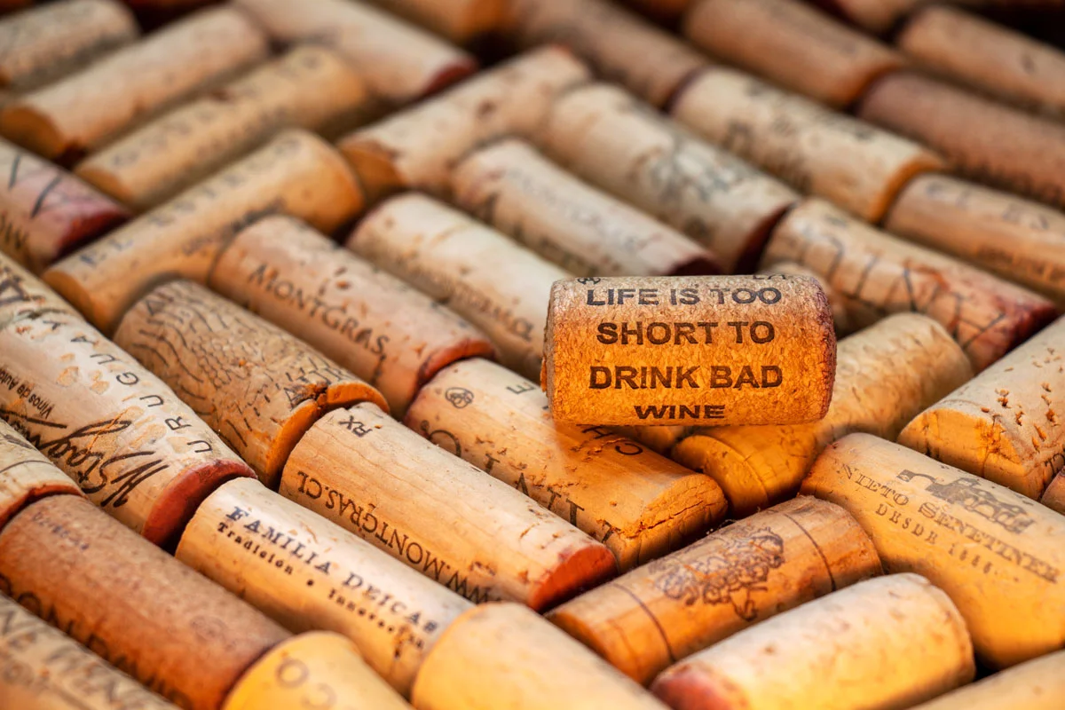 Wein-Korken liegen dicht nebeneinander, einer davon trägt die Aufschrift Life is too short to drink bad wine.