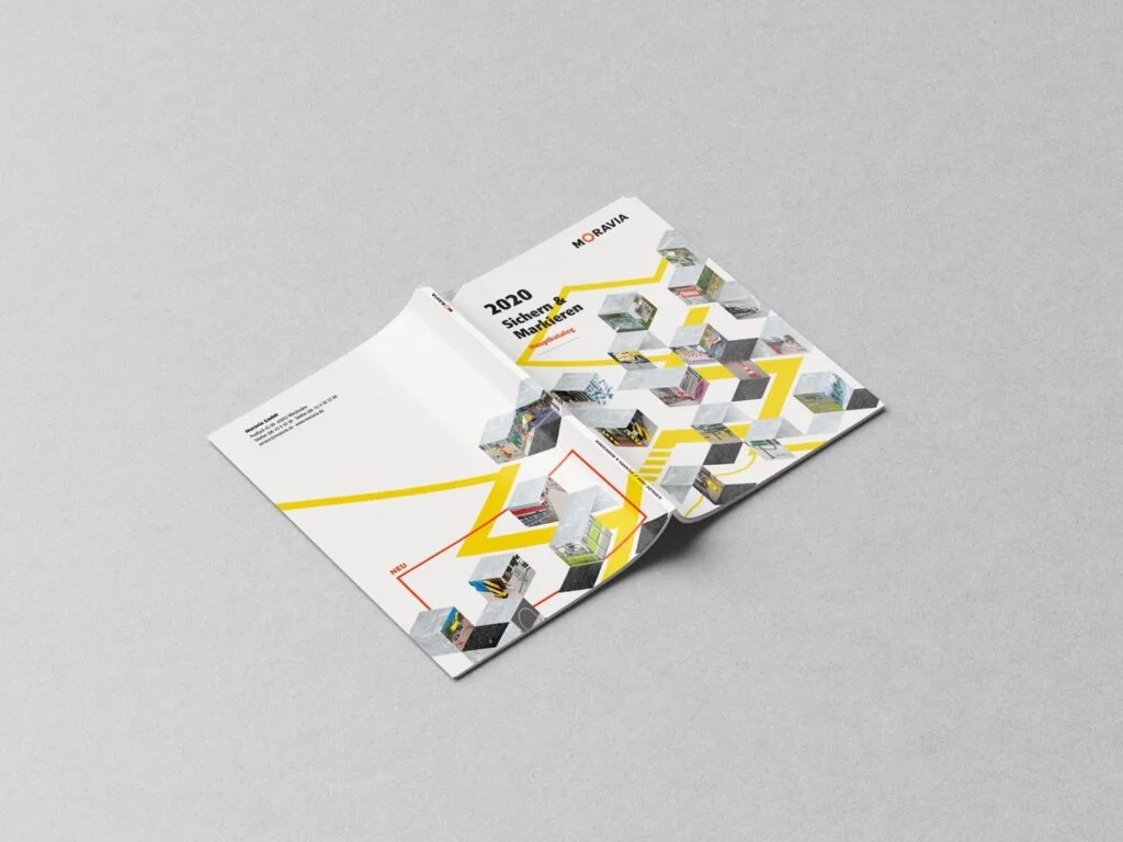 Aufgeklappter Katalog mit dem Titel 2020 Sichern & Markieren von Moravia auf grauem Untergrund, mit grafischen Würfeln und gelben Linien.