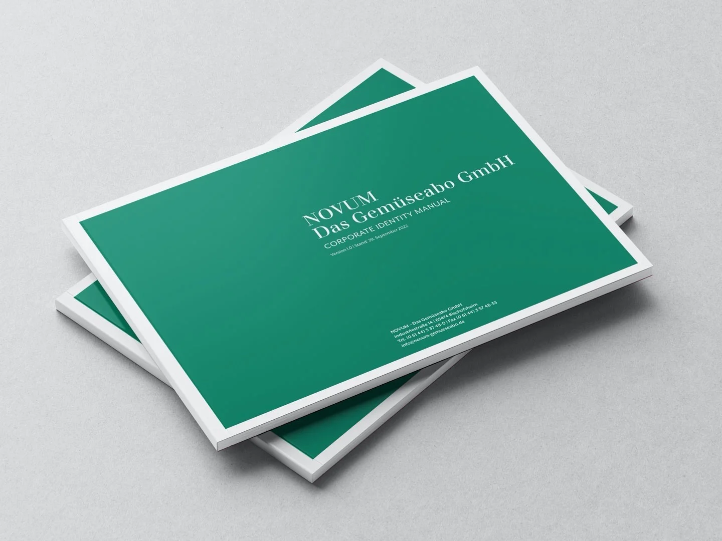 Zwei grüne Broschüren mit weißem Rand liegen auf einem grauen Untergrund, Titel NOVUM Das Gemüseabo GmbH Corporate Identity Manual.