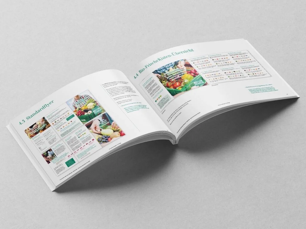 Aufgeschlagenes Buch mit Seiten zu Bio-Frischekisten und Standardflyern, die Bilder von Obst und Gemüse sowie Text enthalten.
