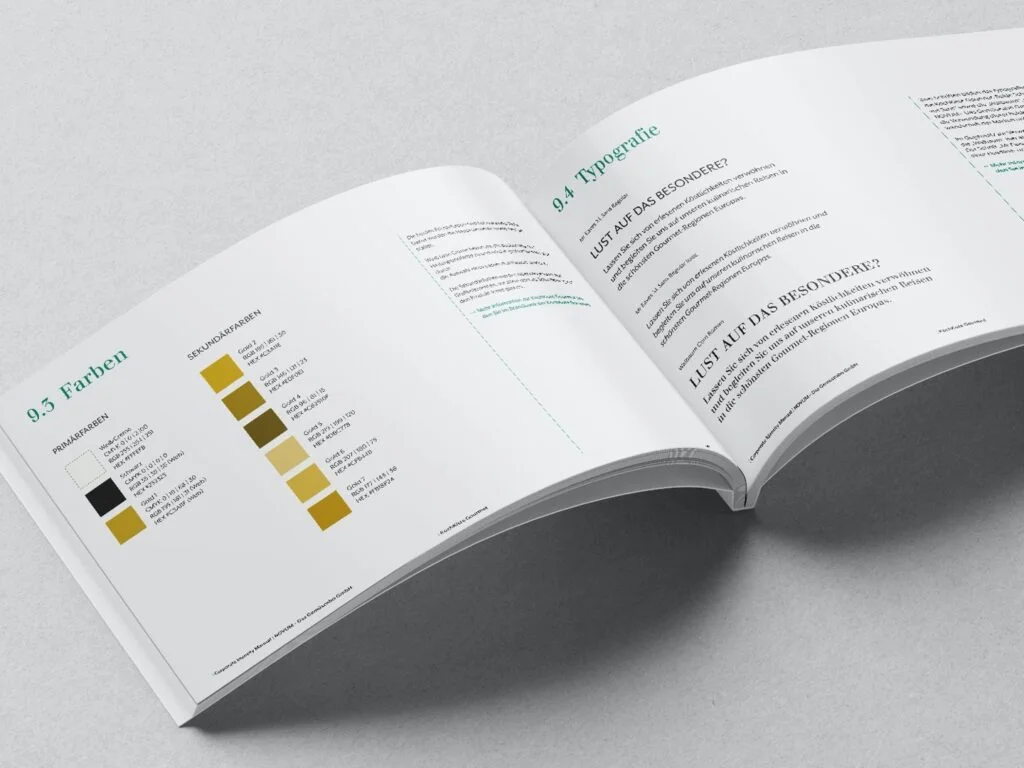 Offenes Buch mit Farbpalette und Typografie-Anleitung in deutscher Sprache auf grauem Untergrund.