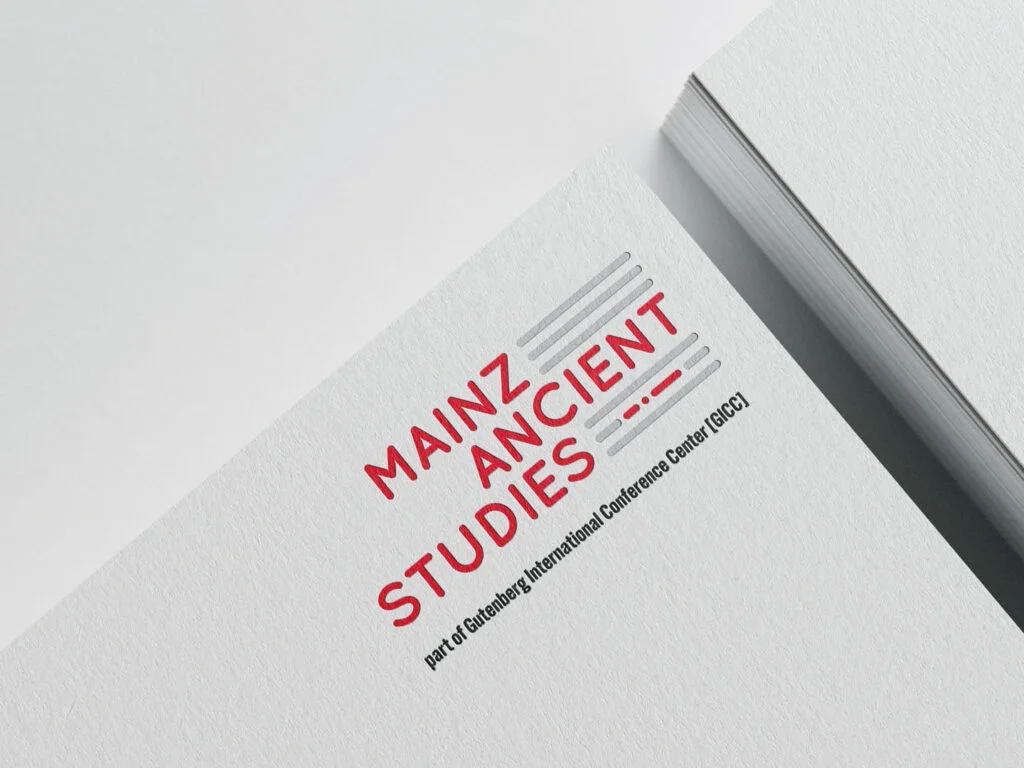 Logo mit rotem Schriftzug Mainz Ancient Studies und grauen Linien auf weißem Papier, darunter Text part of Gutenberg International Conference Center (GICC)