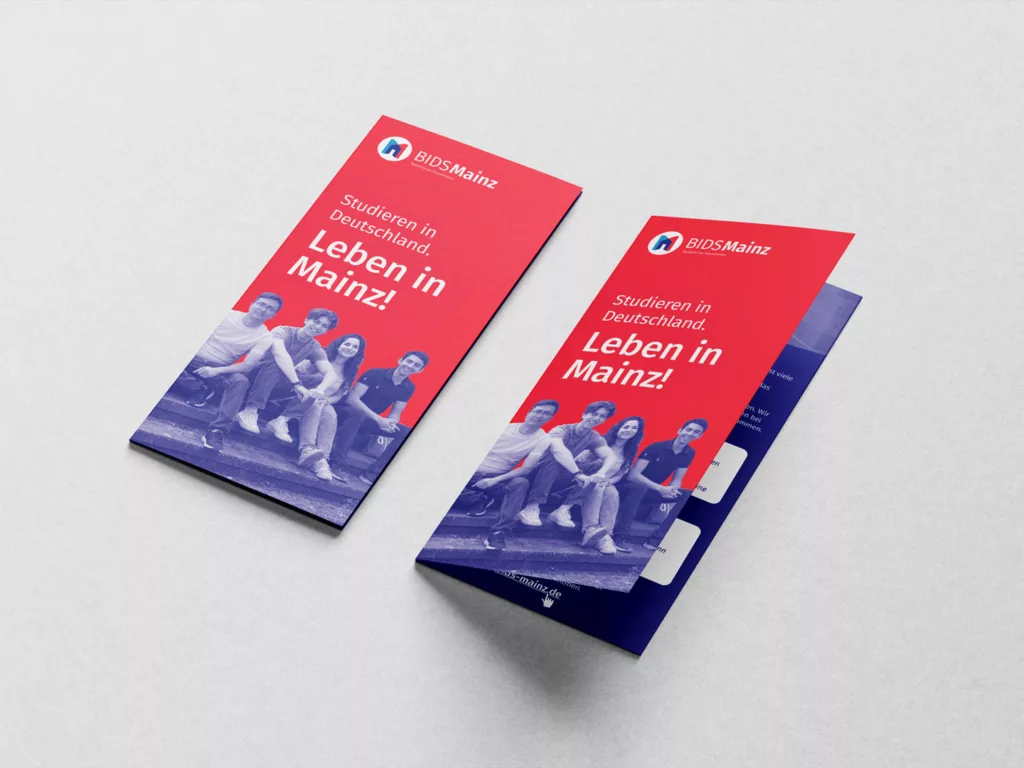 Zwei rote Flyer mit der Aufschrift Studieren in Deutschland Leben in Mainz und einem Bild von vier jungen Menschen, die auf einer Treppe sitzen.