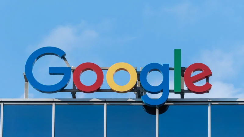 Buntes Google-Logo auf einem Gebäude vor blauem Himmel.