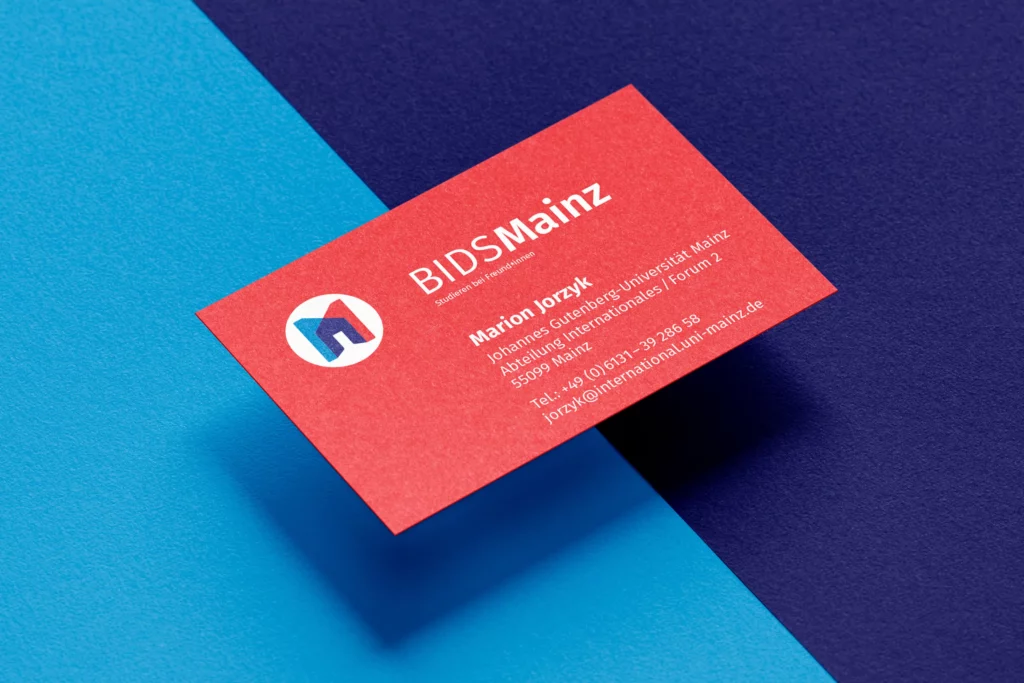 Rote Visitenkarte von BIDS Mainz mit Kontaktdaten von Marion Jorzyk auf blau-dunkelblauem Untergrund.